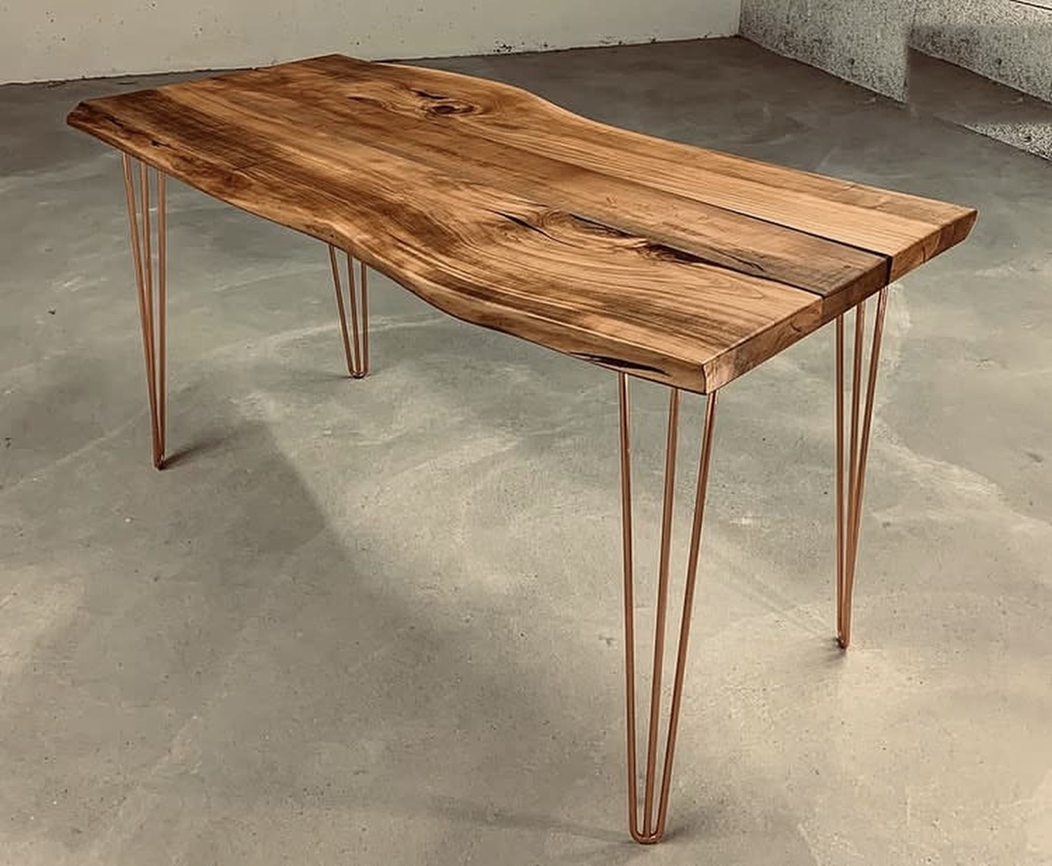 Live-edge cherry table on gold hairpin legs in a concrete room