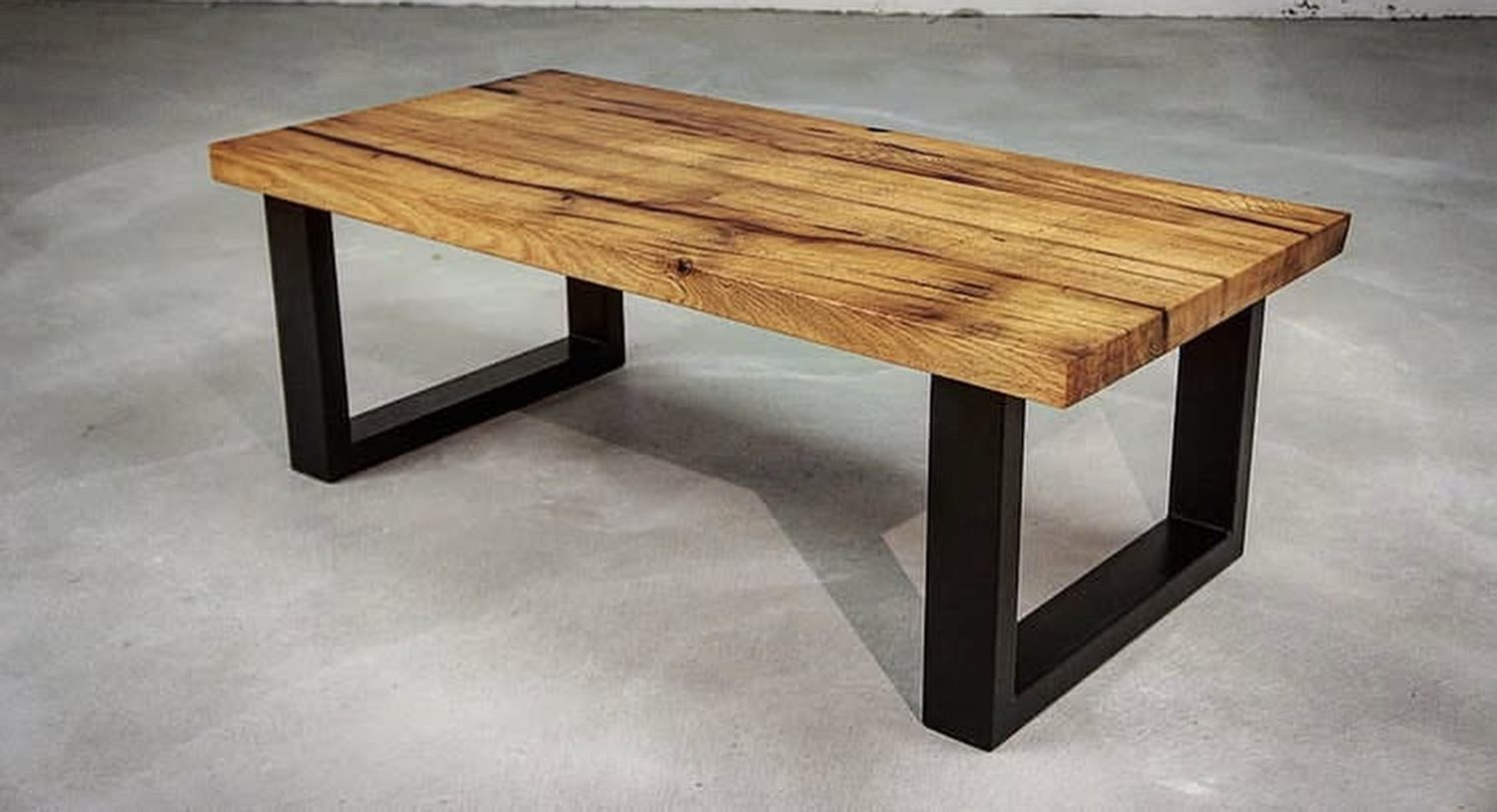 Oak coffee table on black steel box legs in a concrete room