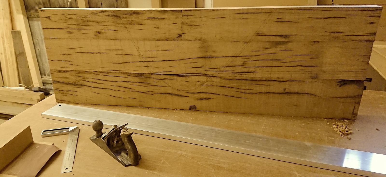 Glued oak panel on the bench with a hand plane and straightedge